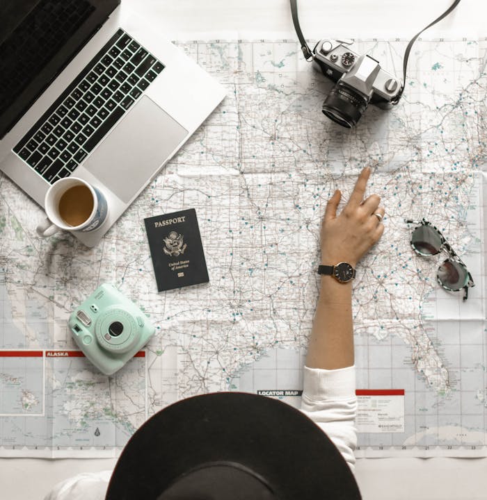 Mastering the First Impression: Your intriguing post title goes here Hand on map with camera, passport, laptop, and coffee, perfect for travel planning inspiration.